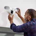 Man installing CCTV on wall to improve home security.